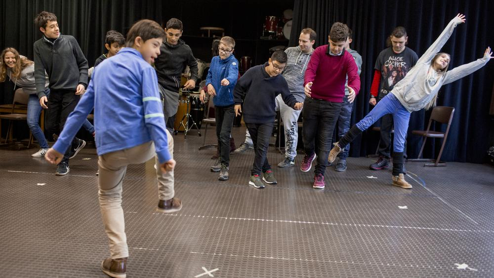 Jungen und Mädchen bewegen sich in einer Theaterhalle