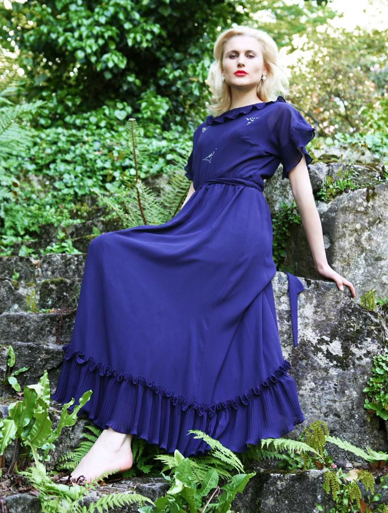 Das transsexuelle Model Elina posiert in langem blauem Kleid auf einer Felstreppe