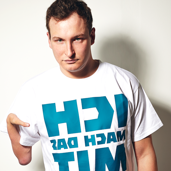 Junger Mann mit dunklen kurzen Haaren schaut mit ernstem Gesicht in die Kamera.