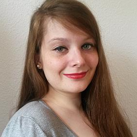 Junge Frau mit rotblonden langen Haaren lächelt in die Kamera.