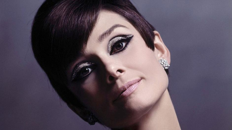 Portraetfoto von Audrey Hepburn in jungen Jahren mit kurzen Haaren und keck zur Seite gelegtem Kopf