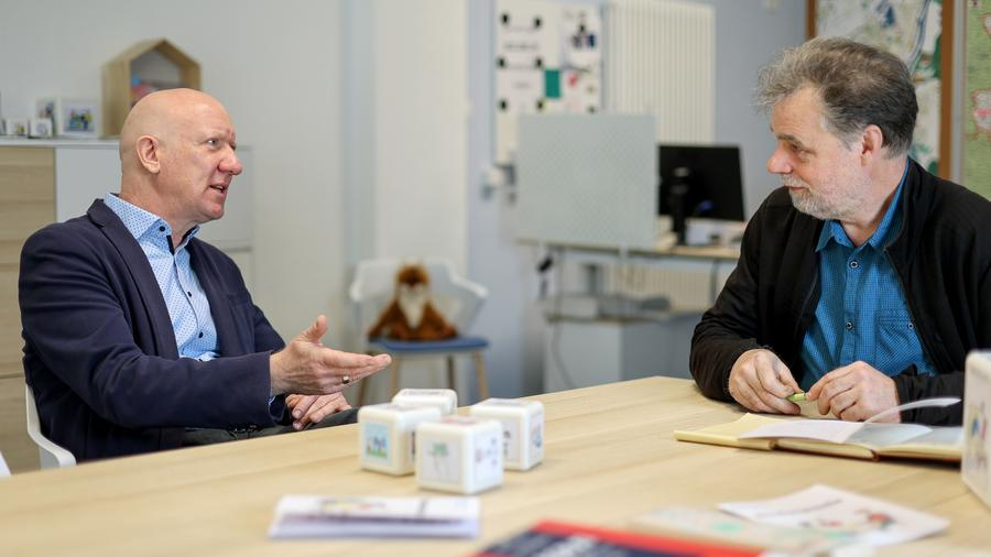 Zwei Männer mittleren Alters unterhalten sich an einem Besprechungstisch