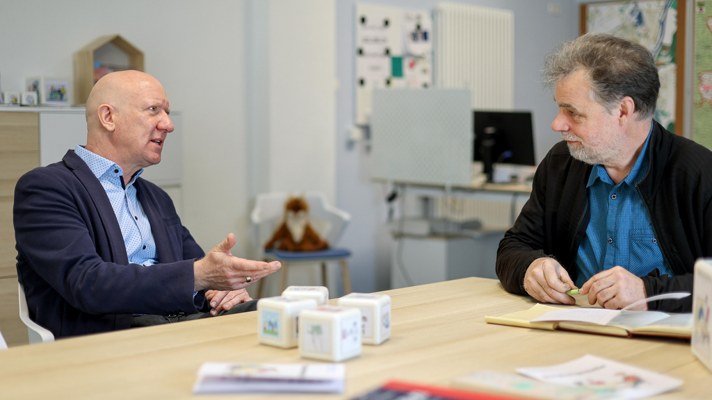 Zwei Männer mittleren Alters unterhalten sich an einem Besprechungstisch