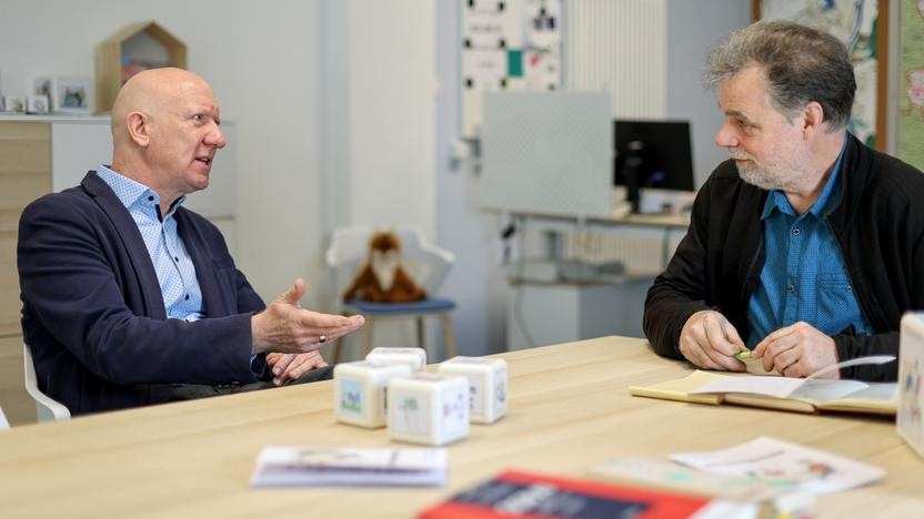 Zwei Männer mittleren Alters unterhalten sich an einem Besprechungstisch