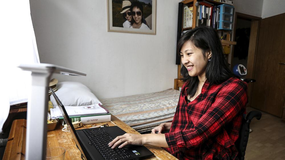 Simone schreibt an ihrem Laptop in ihrem Zimmer.