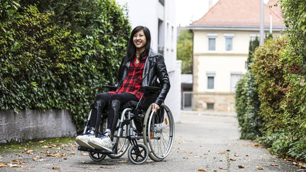 Die Reise-Bloggerin Simone L. in ihrem Rollstuhl vor einer grünen Hecke.