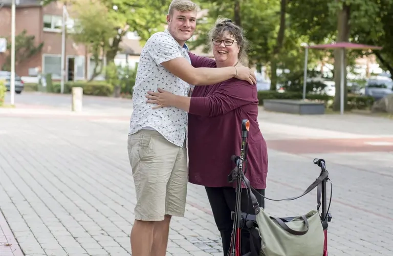 Eine Frau mit Rollator und ein Mann umarmen sich