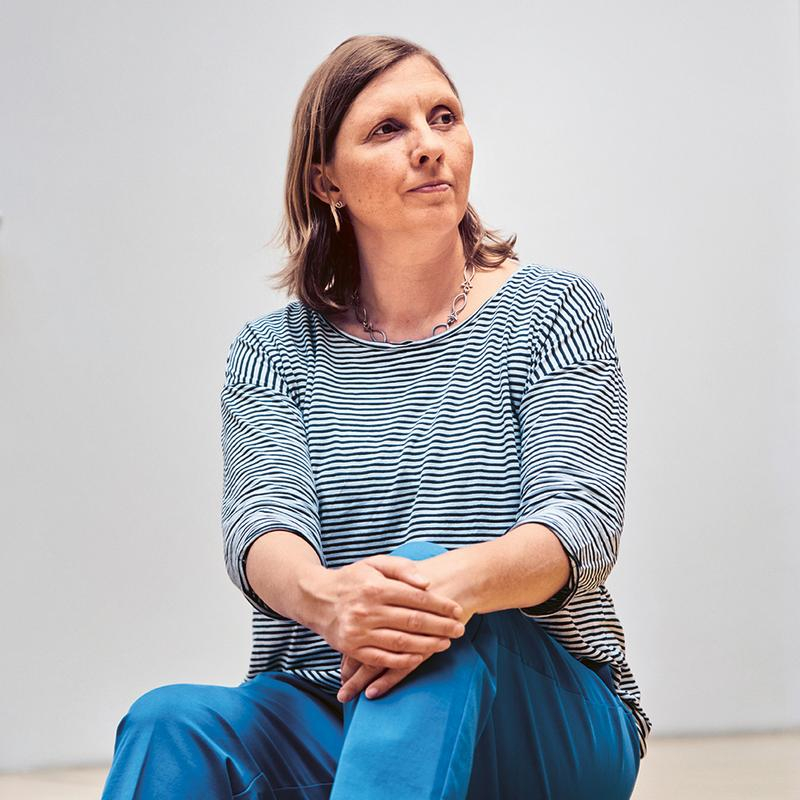 Frau sitzt auf breiten Stufen in einem Raum