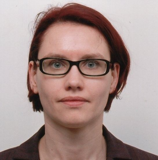 Porträt einer Frau mit kurzen roten Haaren und Brille.