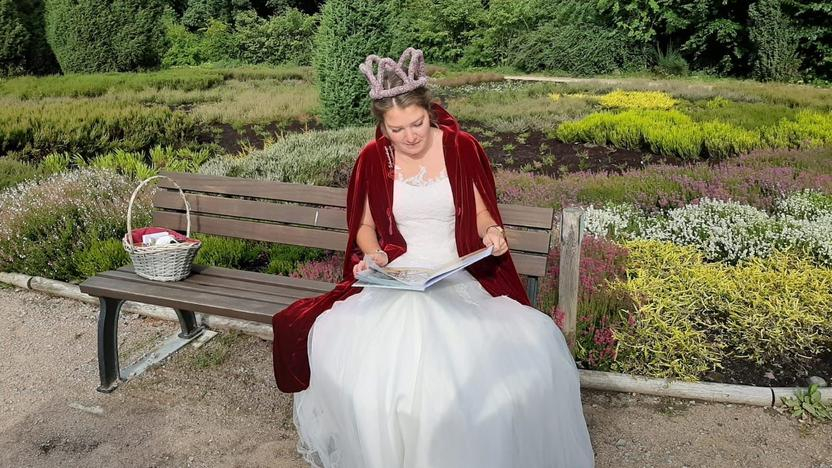 Schneverdinger Heidekönigin liest im Park ein Bilderbuch vor