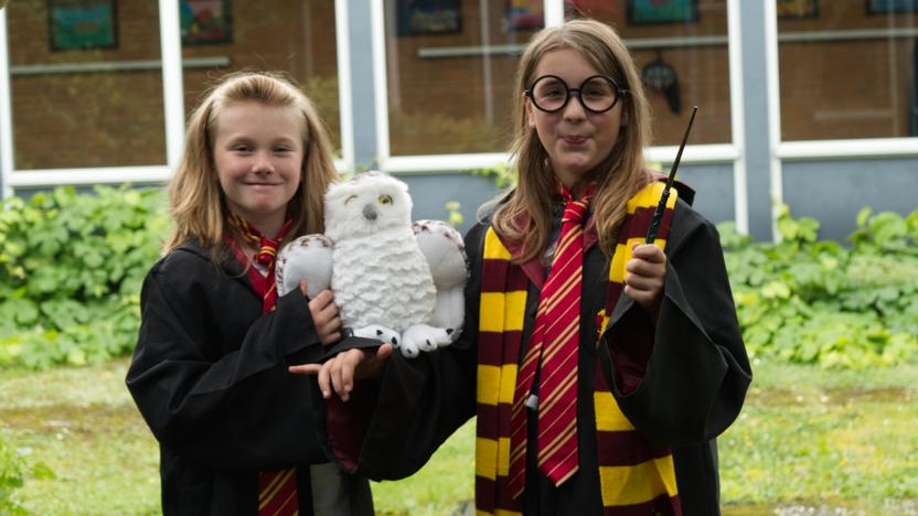 Zwei Kinder sind als Zauberlehrlinge verkleidet, mit Zauberstab und der Eule Hedwig