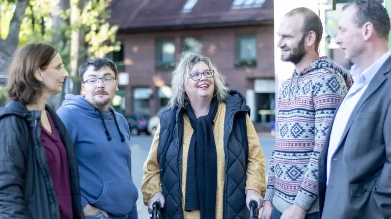 Eine Gruppe von Menschen mit und ohne Behinderung an einer Bürgerbus-Haltestelle