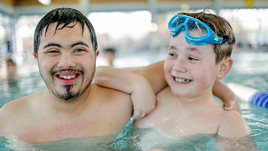Zwei JUgendliche stehen im Schwimmbecken nebeneinander.