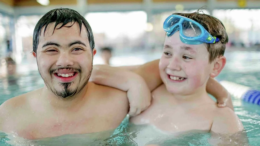 Zwei JUgendliche stehen im Schwimmbecken nebeneinander.