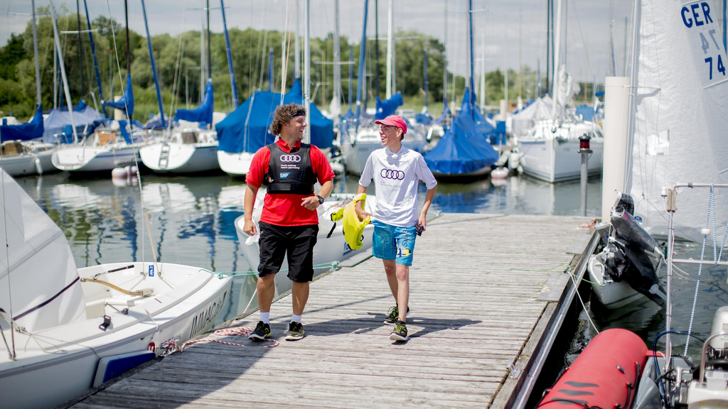 Zwei Männer laufen einen Steg entlang und lachen.