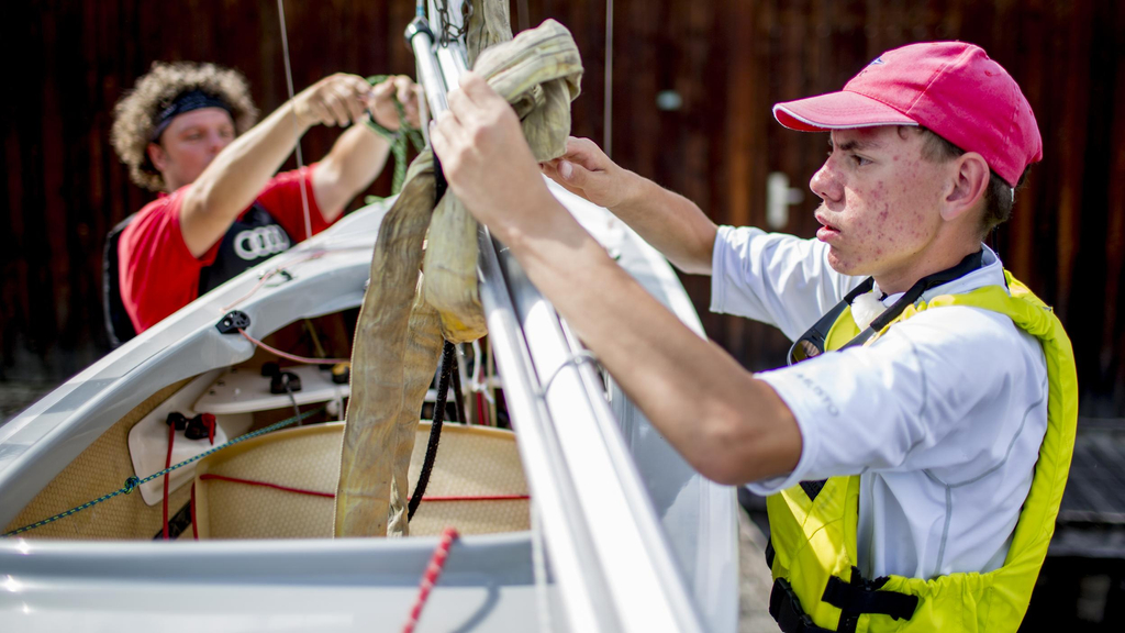 Zwei Männer bereiten ein Segelboot vor.