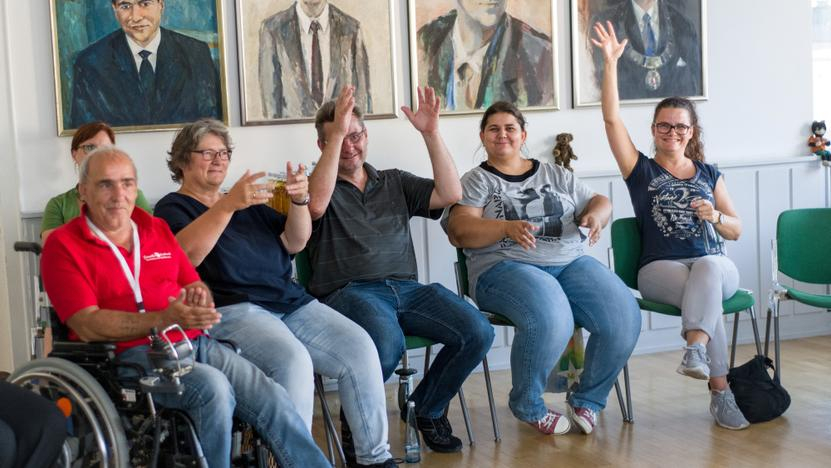 Ein Rollstuhlfahrer sitzt zusammen mit anderen in einem Halbkreis
