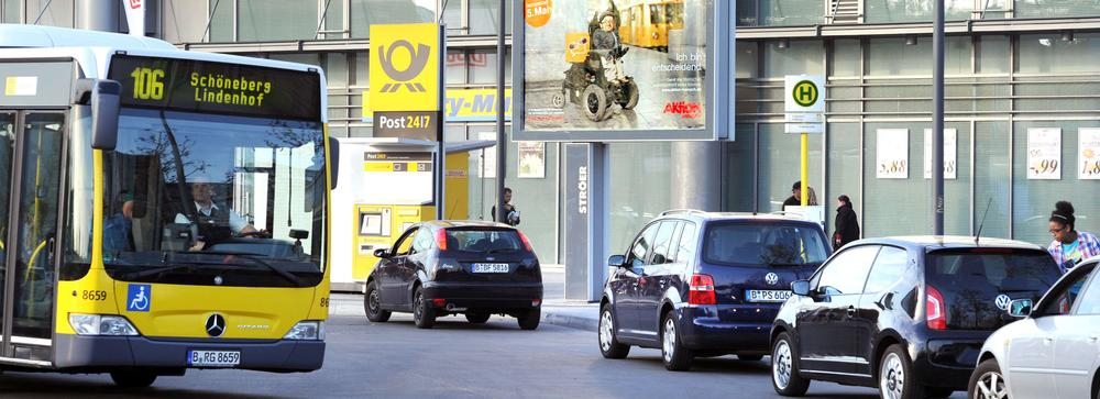 Ein Bus fährt auf eine Haltestelle zu. Ihm entgegen kommen mehrere Autos.