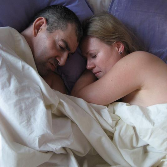 Ein Mann und eine Frau liegen aneinandergeschmiegt im Bett
