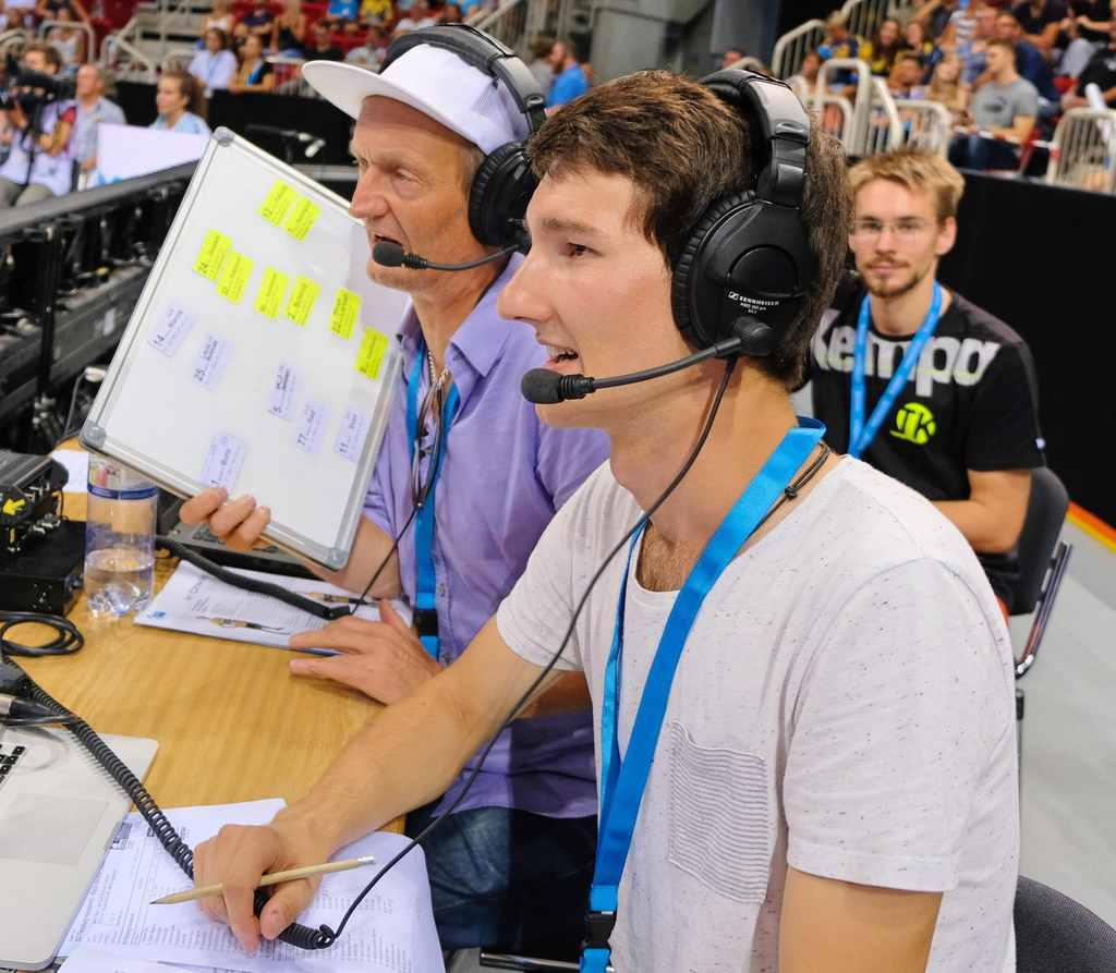 Ein junger Mann bei der Audiodeskription einer Sportveranstaltung in einer Sporthalle