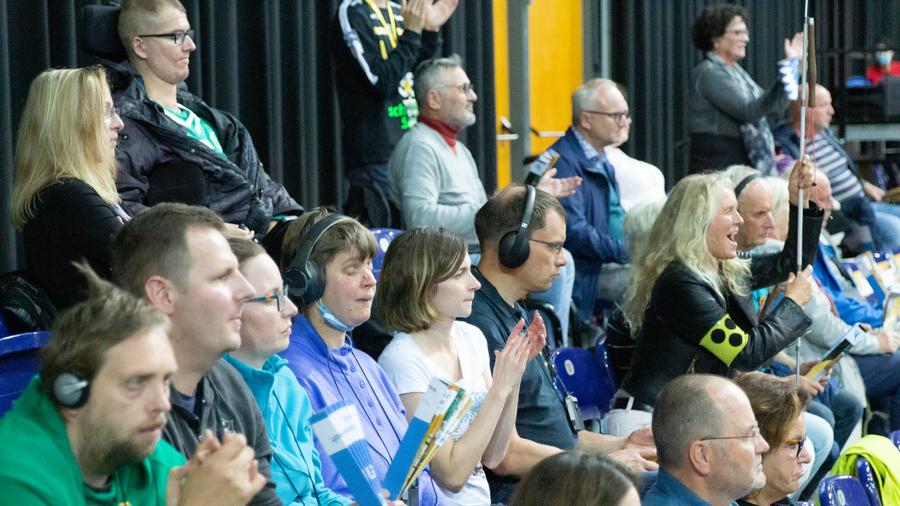Fans, davon viele blind und mit Kopfhörer, während einer Sportveranstaltung in einer Halle