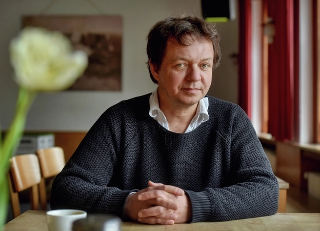 Stefan Reichmann sitzt an einem Tisch und schaut in die Kamera.