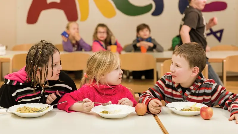 Drei Kinder essen in einer Einrichtung der Stiftung "Die Arche"