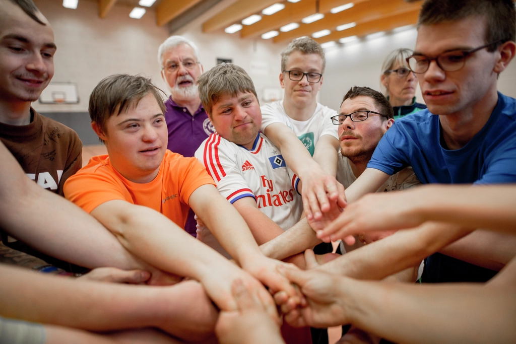 Ein Gruppe von Menschen mit und ohne Behinderung fassen sich gemeinsam an den Händen.