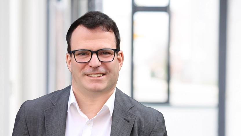 Matthias Tobies, ein Mann mit kurzen dunklen Haaren und Brille, lächelt in die Kamera.