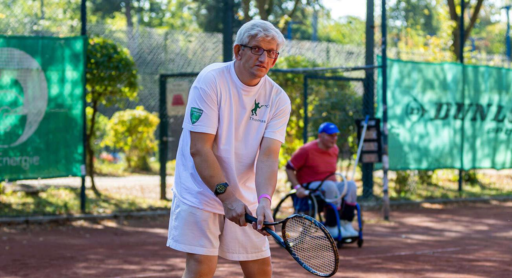 Tennisspieler beim inklusiven Training auf dem Sandplatz
