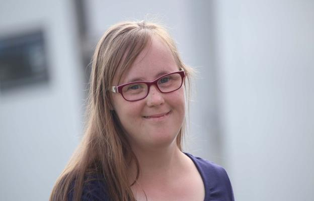 Porträt von Carina Kühne: eine junge Frau mit langen blonden Haaren und Brille.