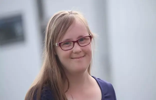 Porträt von Carina Kühne: eine junge Frau mit langen blonden Haaren und Brille. 