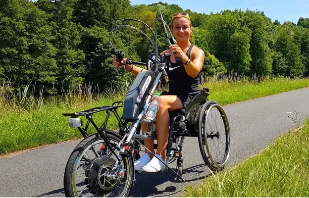 Porträt einer Frau auf einem Handbike. Darunter das Zitat: "Mein größter Träum wäre ein barrierefreier Winkelbungalow für meinen Schatz, unsere Katze und mich, mit Kaminofen, kleiner Terasse mit Garten und einer Doppelgarage." Dunja, 37, Dipl. Sozialpädagogin