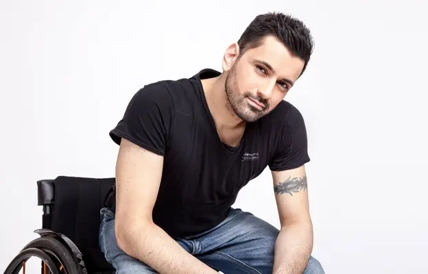 Porträt eines Mannes im Rollstuhl. Darunter das Zitat: "Mein Traum ist es, eines Tages ein Stadion mit 25.000 Rollstuhlfahrern zu füllen. Wenn jeder von ihnen eine Begleitperson mitbringt, dann gäbe es mit 50.000 Menschen die größte Inklusions-Comedy-Show der Welt!" Tan Caglar, Comedian