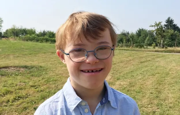 Porträt eines blonden Jungen mit Down-Syndrom. Darunter das Zitat: "Mein größter Wunsch ist es, dass ich immer jemanden zum Spielen habe!" Thibaud, 10 Jahre