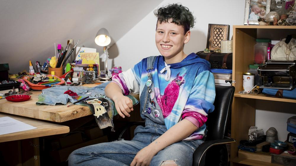 René sitzt an seinem Schreibtisch und lächelt in die Kamera.