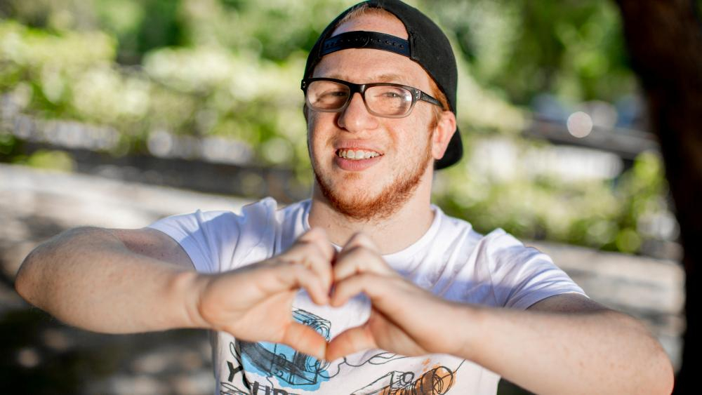 Ein Mann mit Kappe und Brille bildet mit seinen Händen ein Herz.