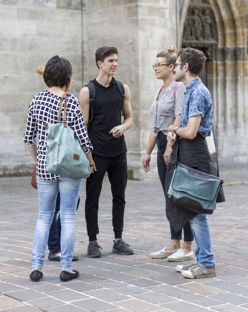 Fünf junge Menschen stehen in einem Halbkreis und unterhalten sich
