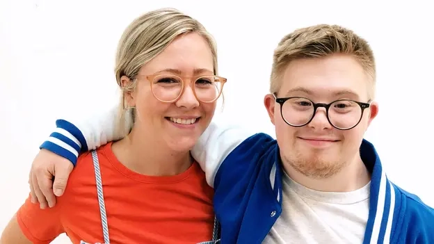 Die beiden Geschwister Tabea und Marian lächeln Arm in Arm in die Kamera.