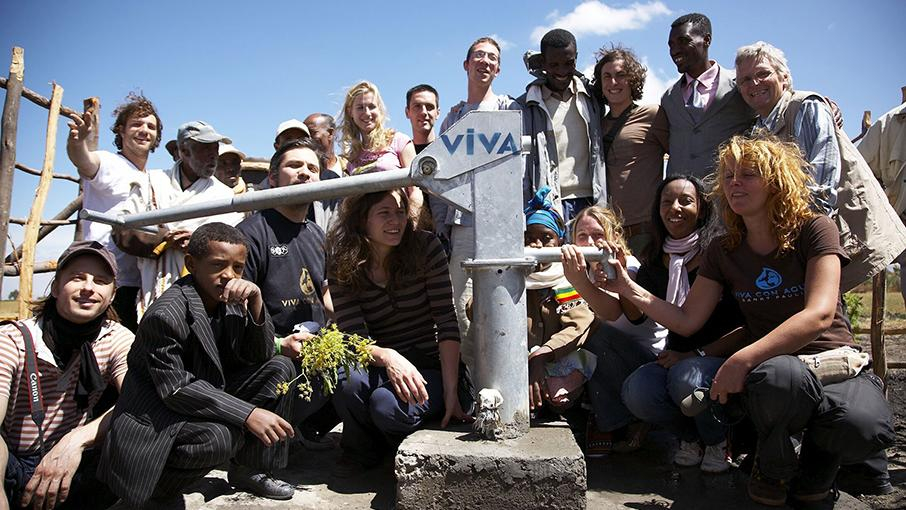 Gruppenfoto junger Leute vor einer Wasserpumpe.