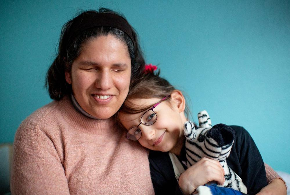 Eine blinde Frau hält ihre Tochter im Arm.