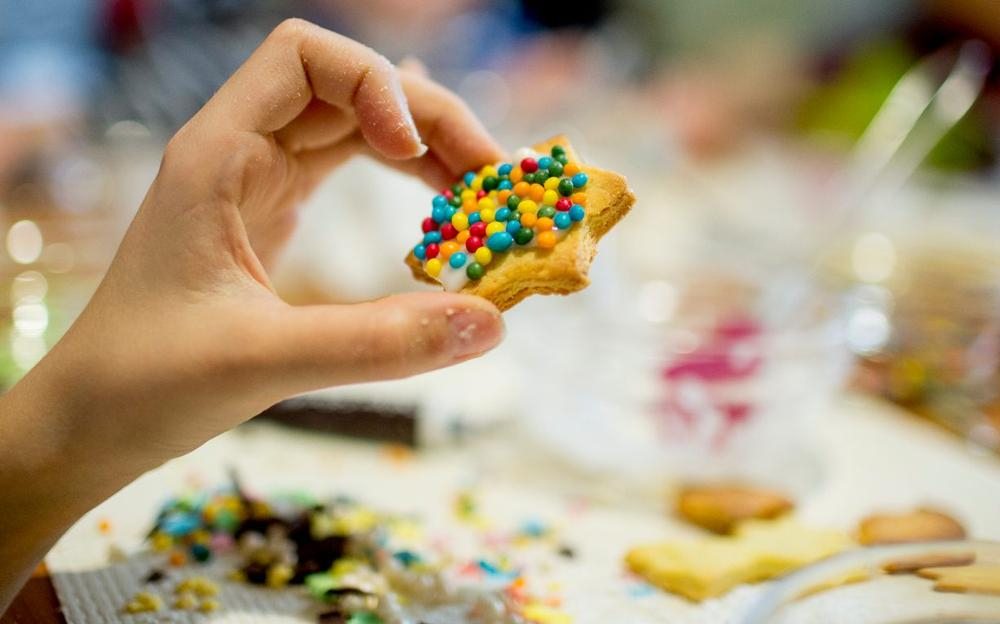 Eine Hand hält einen Keks mit bunten Streuseln.