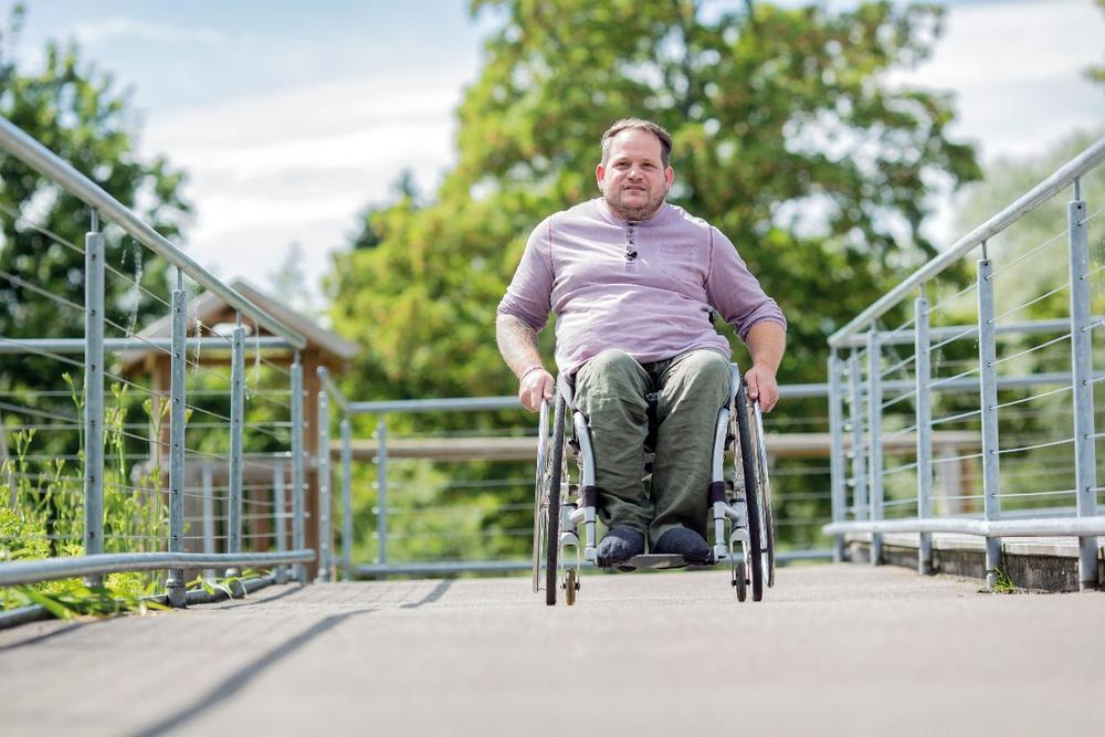 Ein Mann im Rollstuhl fährt über eine Rampe.