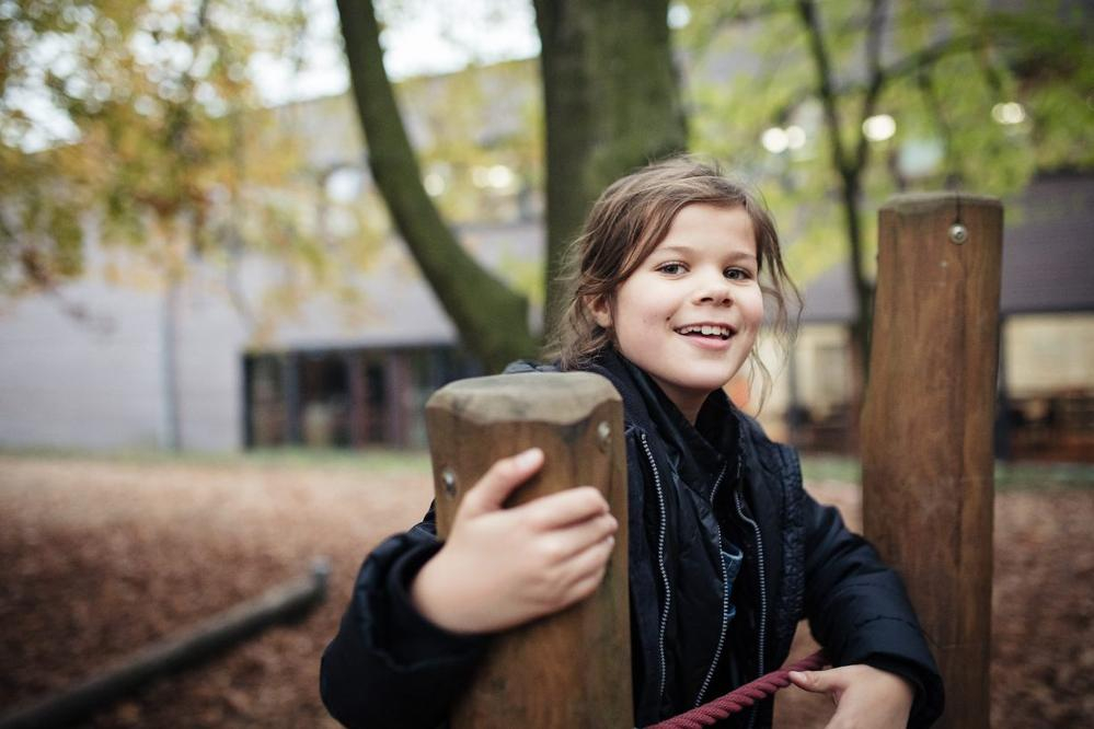 Ein Mädchen steht auf einem Klettergerüst.
