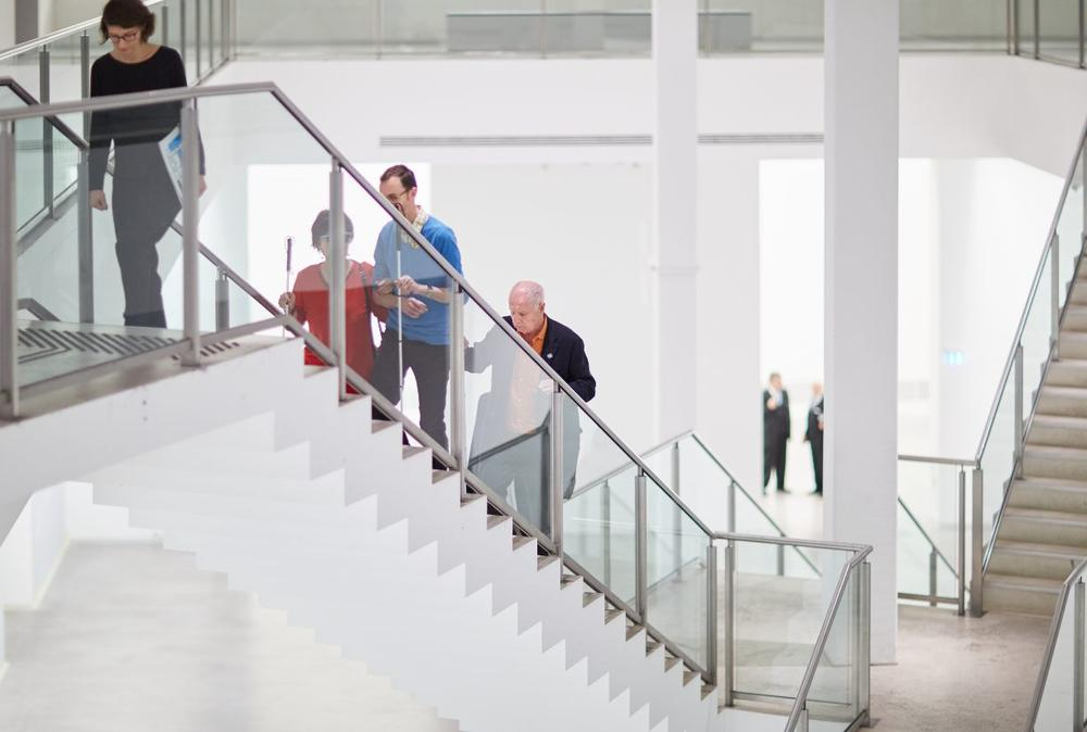 Mehrere Menschen mit und ohne Behinderung gehen eine Treppe herauf.