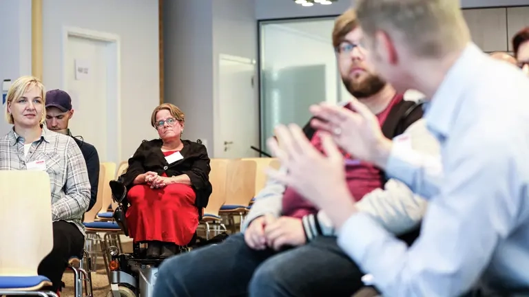 Ein Mann spricht, mehrere andere Personen hören zu